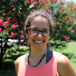 Lead health coach Natlalie, wears a pink shirt and stands in front a flowering tree