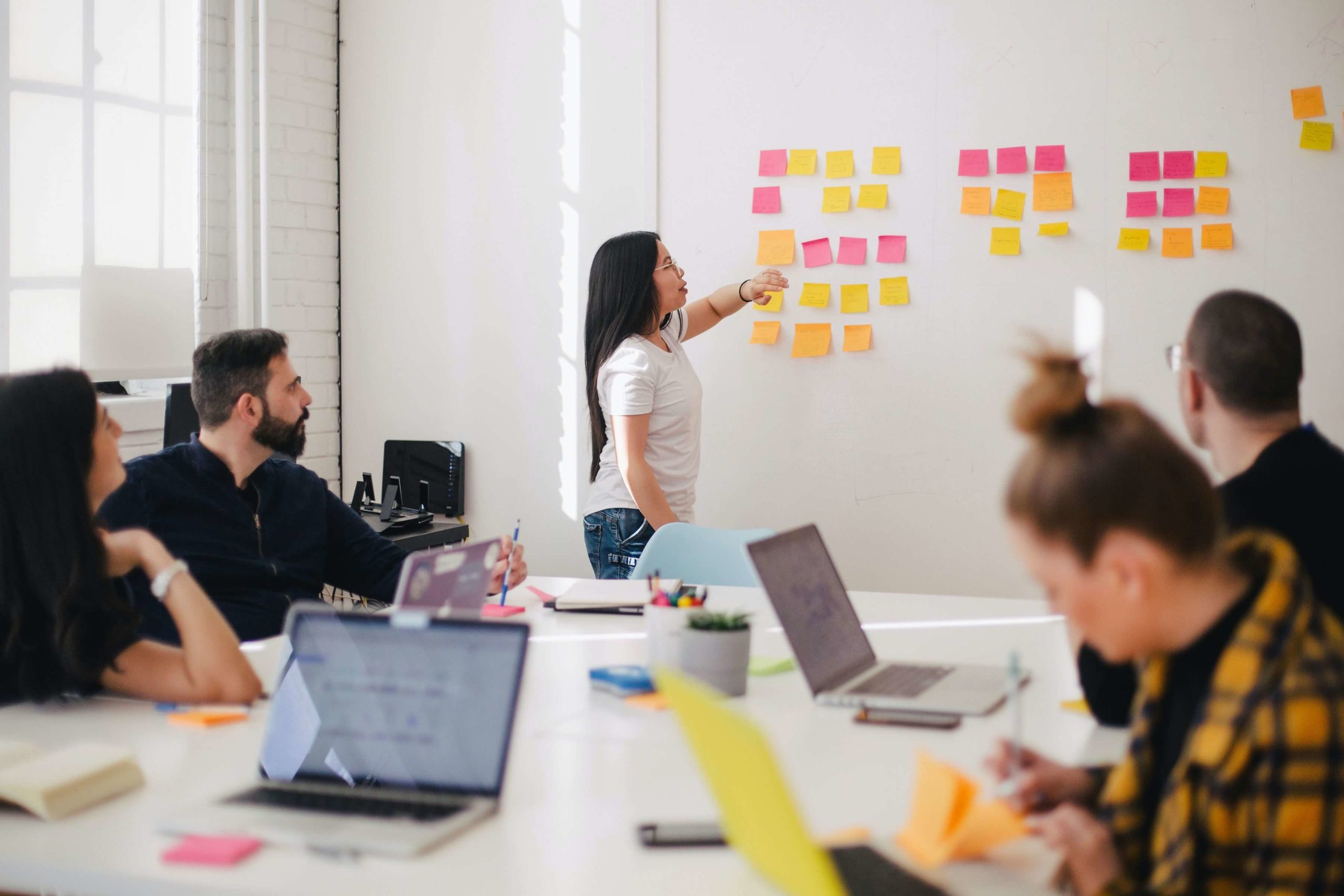 Woman placing sticky notes on white board during a planning meeting