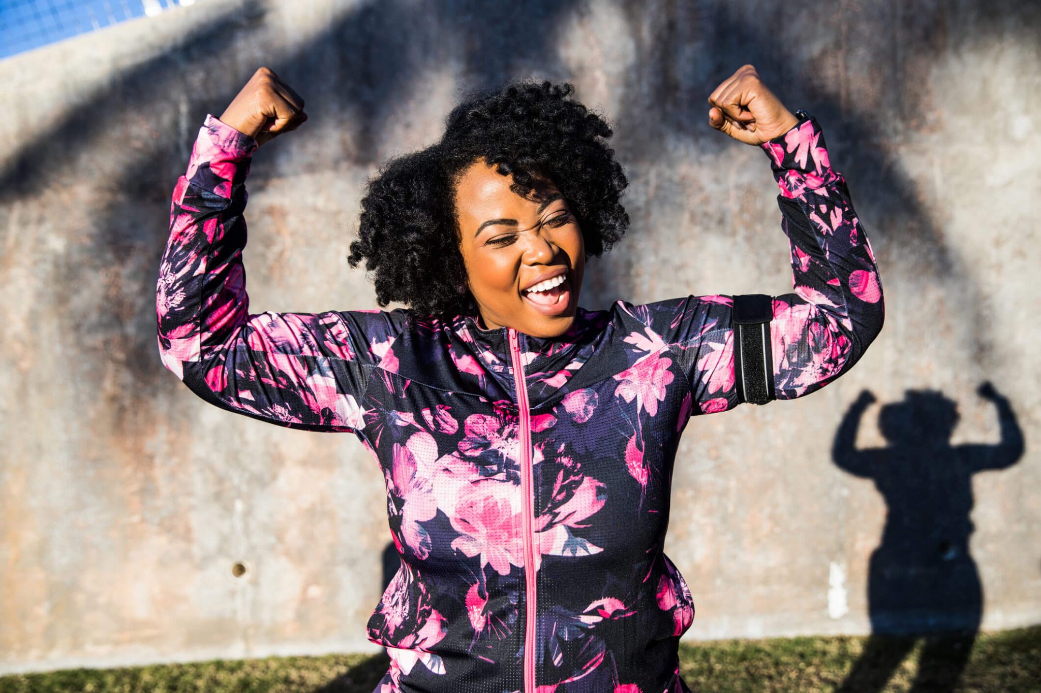 A woman flexing her arms for a photo and smiling