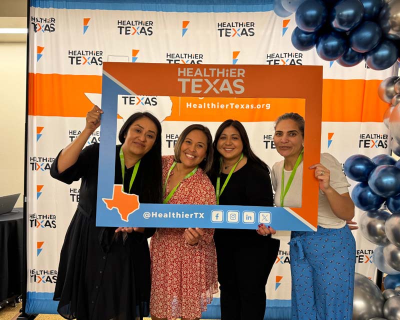 Four women holding a Healthier Texas frame at a Healthier Texas event