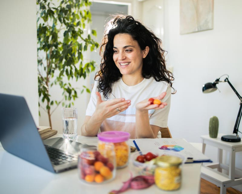 A woman holding cherry tomatoes on a video conference